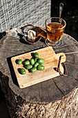 Tea and fresh kiwi berries on a rustic wooden board in the garden