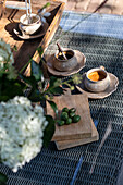 Wooden tray with cups and chopping board on rattan garden table