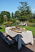 Set garden table with rustic wooden bench in the lush garden