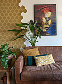 Brown leather sofa with patterned cushions and plants in front of decorative wall design