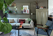 Living room with light grey sofa, green wall paint and various indoor plants