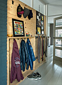 Wardrobe wall made of plywood with skateboards, jackets and caps in the hallway