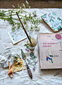 Painting utensils and illustrated botany books on table