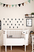 Small white baby cot with cactus wall stickers in the nursery