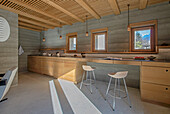 Moderne Küche mit Betonwänden und Holzelementen, Bergblick durch Fenster
