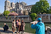 France,Paris,Notre Dame de Paris Cathedral,two days after the fire,April 17,2019,Asian tourists being photographed in front of the cathedral from the quay of Montebello