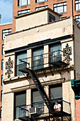 Mann sitzt vor einem traditionellen Wohnhaus in Tribeca, Manhattan, New York, USA