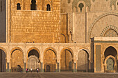 Morocco,People walking across huge courtyard in front of Hassan II mosque,Casablanca