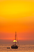 Spanien,Menschen beobachten den Sonnenuntergang von einer Yacht aus, die vor dem Strand von Benirras festgemacht hat, Ibiza