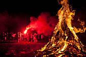 UK,England,Man with red flare beside large bonfire at Battle Bonfire night,East Sussex