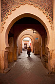 Morocco,Man on moped going through arches in alleyway in Medina of Marrakesh,Marrakesh