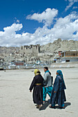 Frauen beim Spaziergang vor dem Leh-Palast, der Leh überragt und dem Potala-Palast in Lhasa, Tibet, nachempfunden ist. Der Palast wurde von König Sengge Namgyal im 17. Jahrhundert erbaut, aber später aufgegeben, als die Dogra-Truppen Mitte des 19. Jahrhunderts die Kontrolle über Ladakh übernahmen.