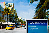 USA.,Florida,Miami,Ocean Drive,South Beach,Bright yellow taxi passing South Beach sign