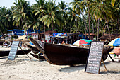 Traditionelle Boote und Strandrestaurants säumen den Strand von Palolem, Goa, Indien.