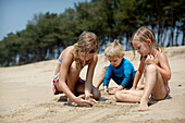 Kinder spielen im Urlaub zusammen und bauen Sandburgen, Turtle Beach, Goa, Indien.