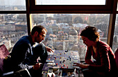 Besucher spielen ein Brettspiel im 26. Stock der Skyline Bar des Reval Hotels, bei Sonnenuntergang, Riga, Lettland.