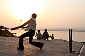 Local boys,on bathing ghat,playing popular national sport of cricket at sunrise. A good hit and the ball goes into the River Ganges. The culture of Varanasi is closely associated with the River Ganges and the river's religious importance.It is the reli
