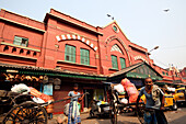 Menschliche Rikschas transportieren Waren auf dem berühmten New Market in der Nähe der Sudder Street, einem beliebten Viertel für preiswerte Unterkünfte für Rucksacktouristen in Kalkutta / Kolkata, der Hauptstadt des Bundesstaates Westbengalen, Indien, Asien.