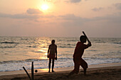 Cricket spielen, der Nationalsport Indiens, am Anjuna Beach bei Sonnenuntergang, Bundesstaat Goa, Indien, Asien.