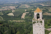 Alter Glockenturm im Zentrum von San Gimignano, einer berühmten mittelalterlichen Stadt auf einem Hügel, die für ihre alten Türme und die umliegenden Weinberge und Zypressen in der Toskana berühmt ist. Italien. Juni.