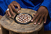 Niger,Nord-Niger,Air Region,Tuareg Mann spielt "Solitaire" traditionelles Spiel,Agadez