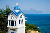 Griechenland,Chalkidiki,Rostige Miniaturkirche am Straßenrand mit dem Berg Athos in der Ferne,Sithonia