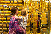 Mutter und Tochter betrachten Goldschmuck, der im Schaufenster eines Geschäfts im Goldsouk verkauft wird, Dubai, Vereinigte Arabische Emirate