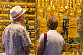 Westliches Paar betrachtet Goldschmuck, der im Schaufenster eines Geschäfts im Goldsouk verkauft wird, Dubai, Vereinigte Arabische Emirate