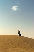 Barefoot Man With Suitcase On Sand Dune,Dubai,United Arab Emirates