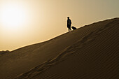 Barefoot Man With Suitcase On Sand Dune At Dusk,Dubai,United Arab Emirates