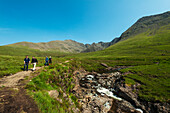 Wanderer, die an einem der Fairy Pools in Coire Na Creiche, Black Cuillin, Isle Of Skye, Schottland, vorbeigehen