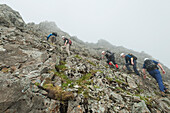 Wanderer beim Aufstieg auf einen steilen Felsen in der Nähe des Gipfels von Sgurr Alasdair in den Black Cuillin, Isle of Skye, Schottland