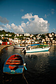 Hafenszene mit bunten Fischerbooten, die in Ufernähe vertäut sind, und der Hafenstadt St. Georges im Hintergrund an einem sonnigen Tag, St. Georges, Grenada, Karibik