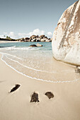Nahaufnahme der Meeresbrandung, die Zickzack-Muster auf dem Sand mit großen Felsbrocken an den Ufern von The Baths, einem berühmten Strand auf den BVI, Virgin Gorda, British Virgin Islands, Karibik