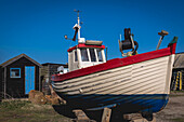 Red,white and blue fishing boat dry docked on the shore in the sunlight,Southwold,Suffolk,England