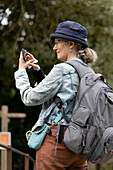 Ältere Frau benutzt ihr Smartphone, während sie im Freien unterwegs ist, Vereinigtes Königreich