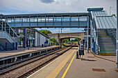 Reife Frau wartet mit Gepäck an einem Bahnhof, Vereinigtes Königreich