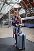 Mature woman waits with luggage at a train station,United Kingdom