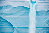 Schmelzwasser ergießt sich von der Oberfläche der Nordaustlandet-Eiskappe über eine Eisklippe, Svalbard, Norwegen