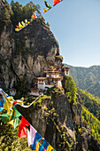 Gebetsfahnen überspannen den Abgrund vor dem Tigernest-Kloster in Bhutan, Paro, Bhutan