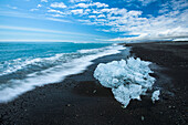 Kleiner Eisberg vom Vatnajokull am Ufer eines schwarzen Sandstrandes, Island