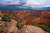 Landschaft des Canyon de Chelley, Arizona. Gewitterwolken ziehen auf, als sich die als "Spinne" bekannte Felsformation aus dem Talboden erhebt. Es ist ein erstaunlicher Ort mit rotem Gestein und ein schönes Beispiel für Erosion bei der Arbeit, Arizona, Vereinigte Staaten von Amerika