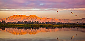 Bei Sonnenaufgang schweben Heißluftballons über dem Nil, Luxor, Ägypten