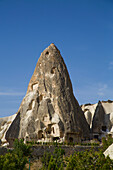 Close-up of a Cave Houses carved into a rock formation peak against a bright blue sky near the town of Goreme in Pigeon Valley,Cappadocia Region,Nevsehir Province,Turkey