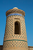 Turm mit dekorativem Muster vor strahlend blauem Himmel in Itchan Kala, Chiwa, Usbekistan