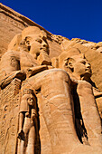 Nahaufnahme von zwei in den Berghang gehauenen Statuen von Ramses II. an der Vorderseite des Großen Sonnentempels von Abu Simbel, Abu Simbel, Nubien, Ägypten