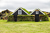 Ein Paar historischer Torfhäuser an einer Touristenattraktion in Westisland, Island