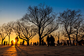 Silhouetten von Bäumen und Touristen bei Sonnenuntergang, Der Sommerpalast, Peking, China