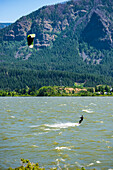 Ein Kite-Surfer genießt die starken Frühlingswinde in der Columbia River Gorge bei Stevenson, Washington.  Die Oregon-Seite der Columbia-Schlucht ist im Hintergrund zu sehen, Stevenson, Washington, Vereinigte Staaten von Amerika