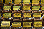 Variety of tea leaves on display for sale with yellow signs and scoops in the baskets,Seville,Spain